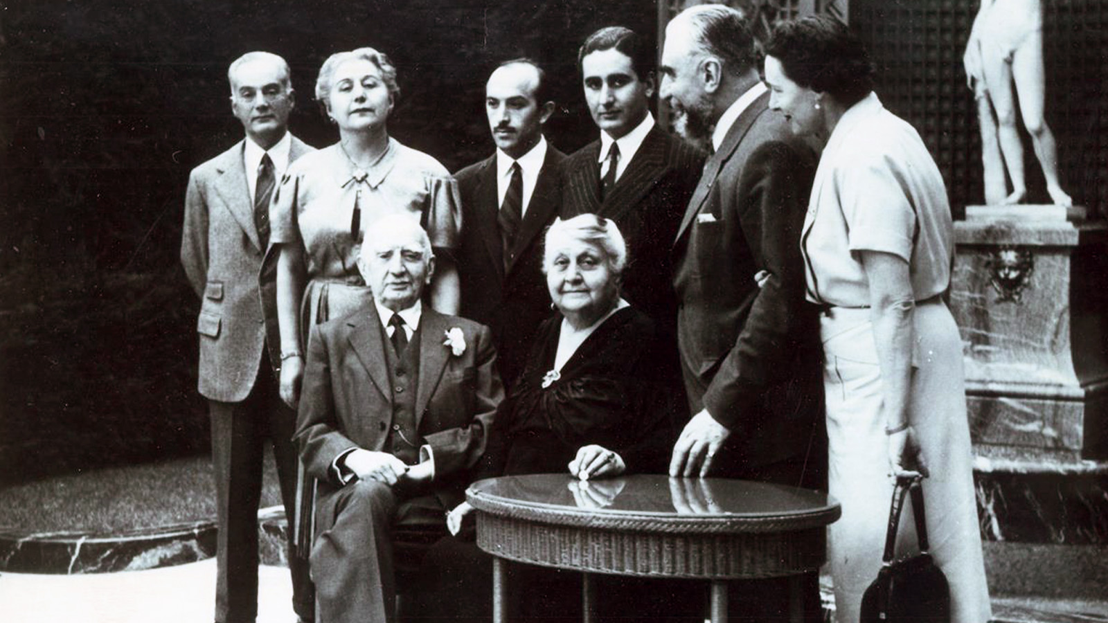 Reproduction of a family photograph, taken on the anniversary of Nevarte and Calouste Gulbenkian's wedding. Nevarte passed away on July 1, 1952, less than a month after the celebration of their 60th wedding anniversary. In the photograph, taken on the terrace of 51 avenue d'Iéna, in the foreground: Calouste and Nevarte Gulbenkian. In the background, from left to right: Kevork Essayan and his wife Rita Essayan Gulbenkian, Roberto Gulbenkian, Mikhael Essayan, Nubar Gulbenkian and his wife, Marie Berthe Edmée de Ayala. Paris, 1952. Calouste Gulbenkian Museum.