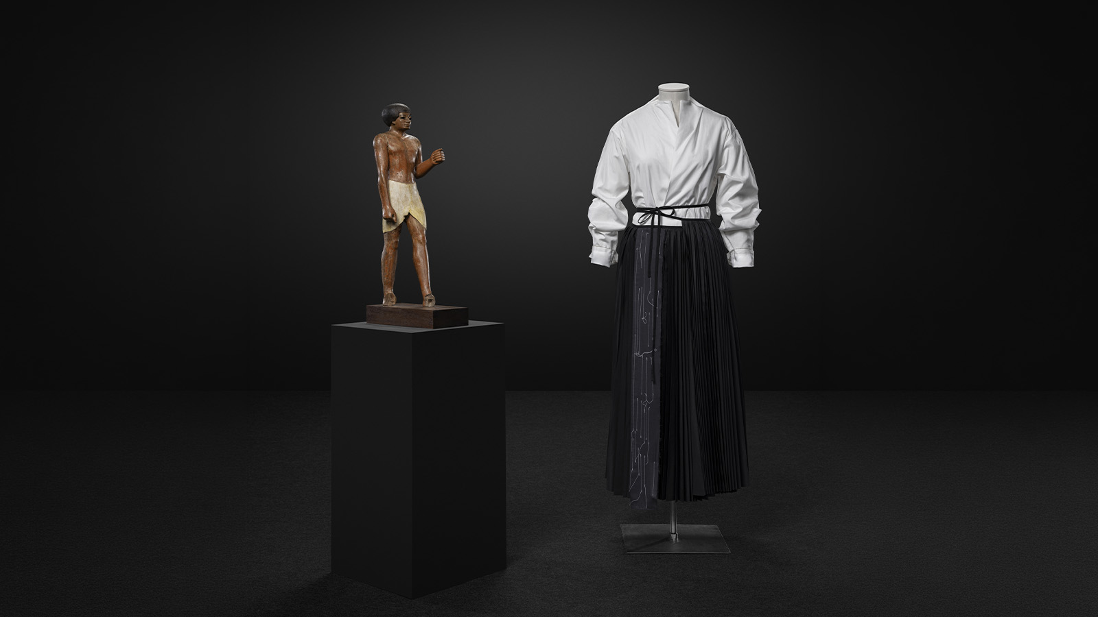 Funerary statue Egypt, Thebes region, Middle Kingdom, 11th dynasty (c. 2000–1990 BCE) Polychrome ebony Calouste Gulbenkian Museum, inv. 142 Yohji Yamamoto Shirt and skirt Prêt-à-porter Fall/Winter 1999/2000 Cotton poplin, wool taffeta and nylon MUDE, Lisbon MUDE/Coleção Francisco Capelo/MUDE.M.0152 Calouste Gulbenkian Foundation. Photo: © Jon Cazenave